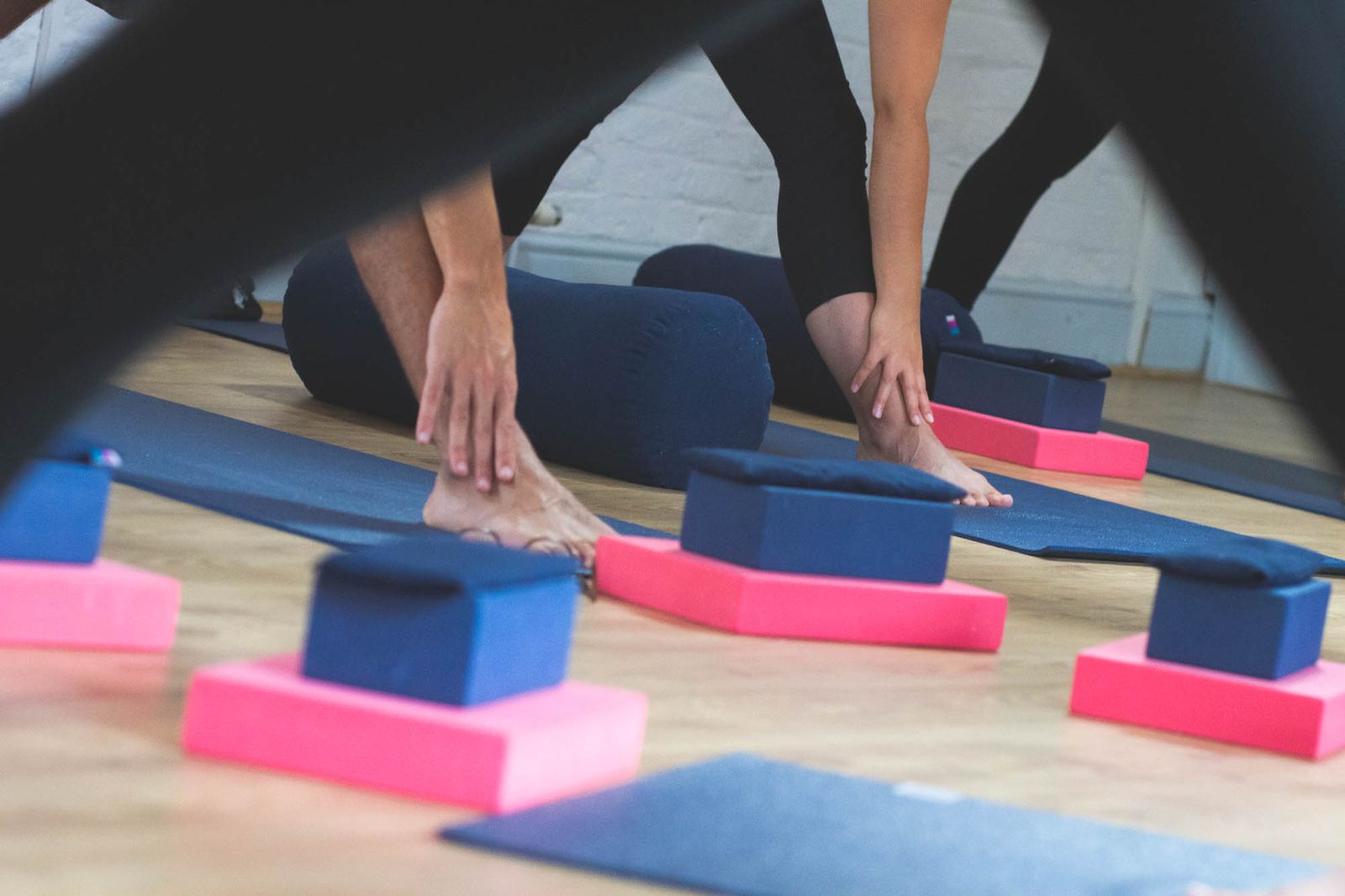 Students in a wide-legged forward fold, with blocks and bolsters set out on their mats