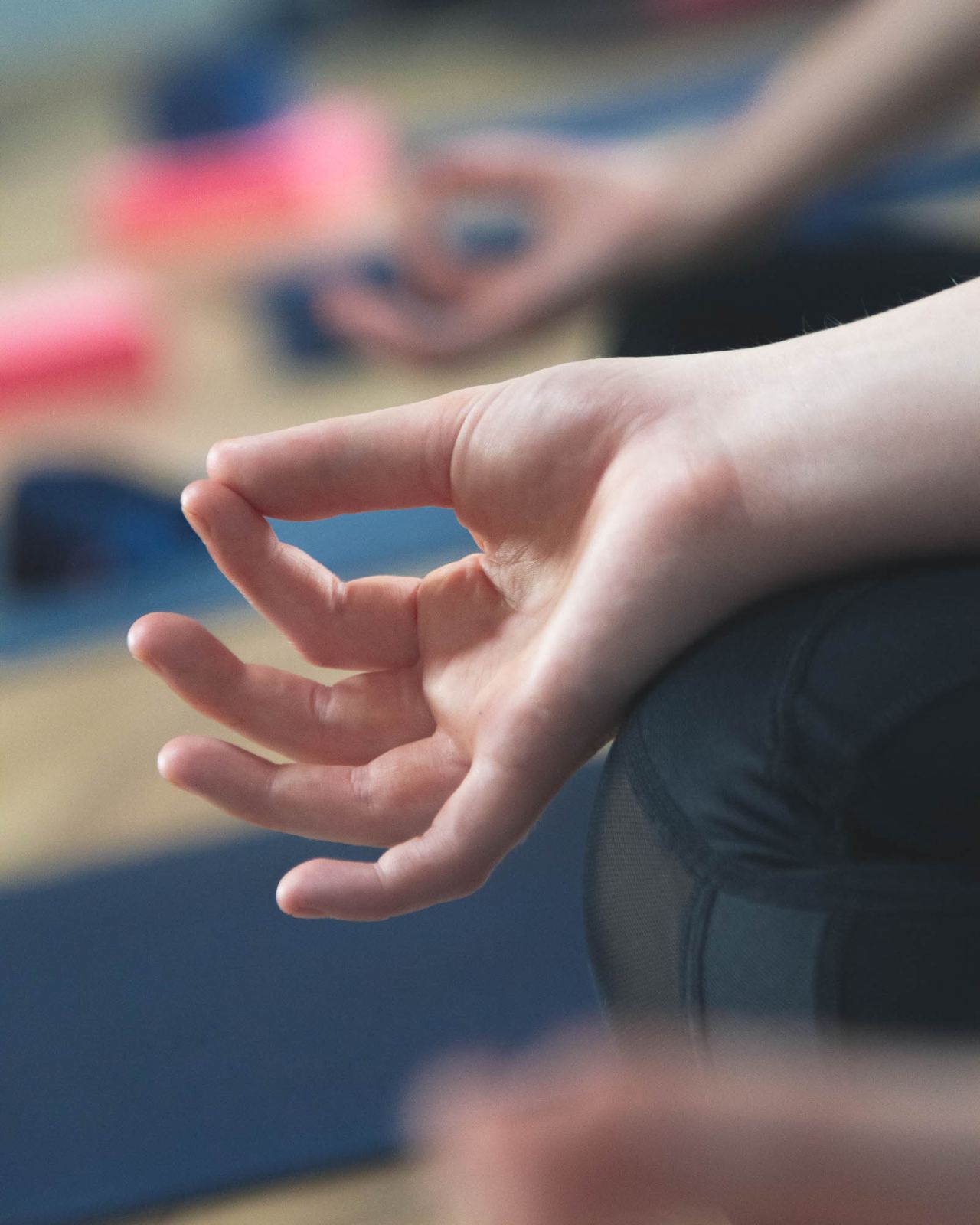 Close-up of a hand resting in a meditation mudra during a class in the studio