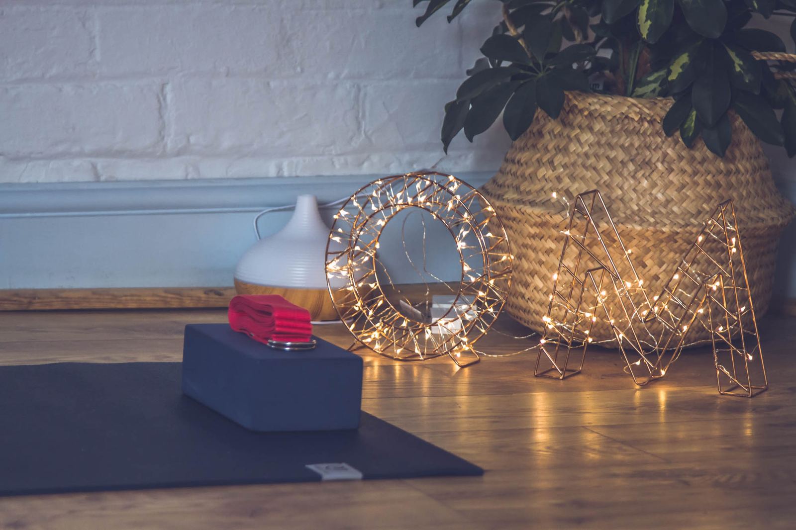 A mat, block and bolster set out in soft fairy-light glow