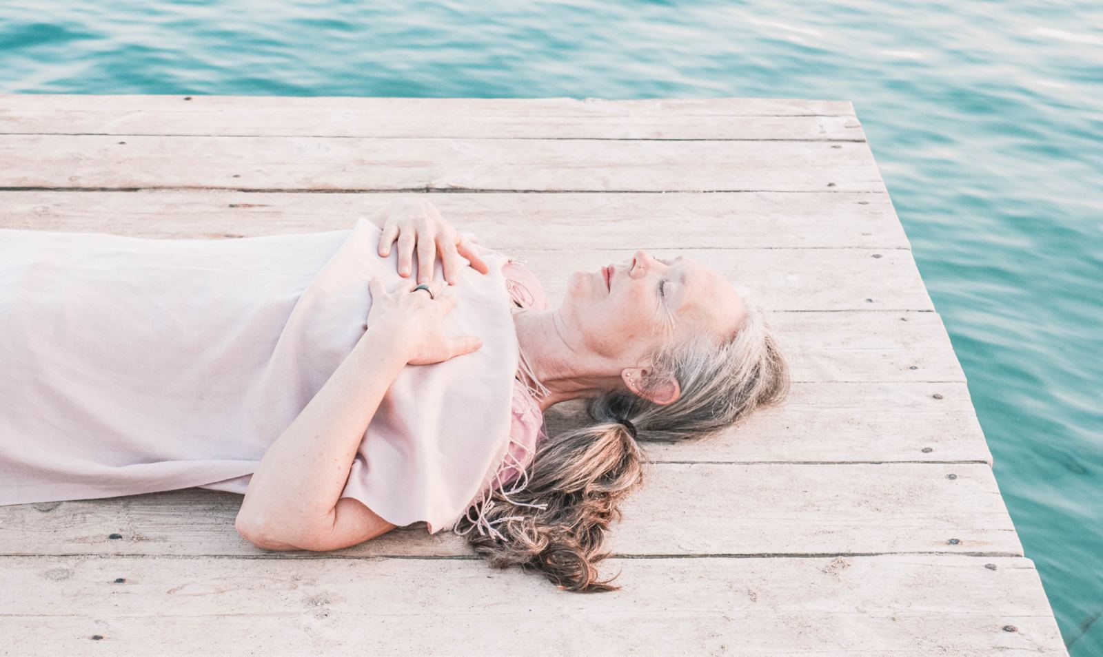 Melanie Cooper lying in deep relaxation on a wooden jetty above the sea