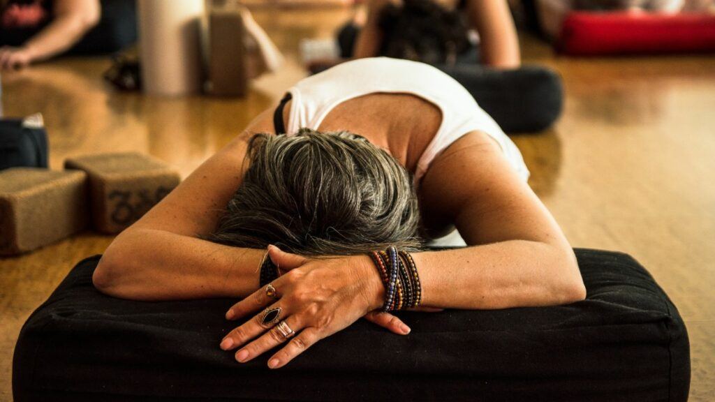 A student resting forward over a bolster during a Yin Yoga class