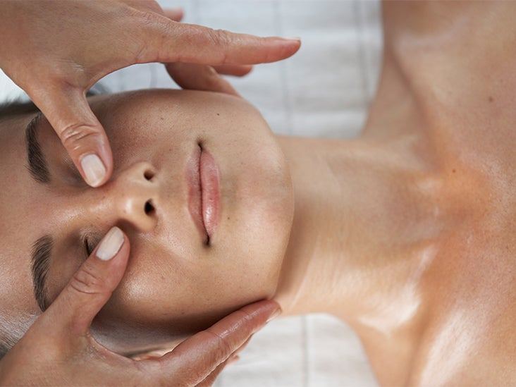 A therapist’s hands gently massaging a client’s face