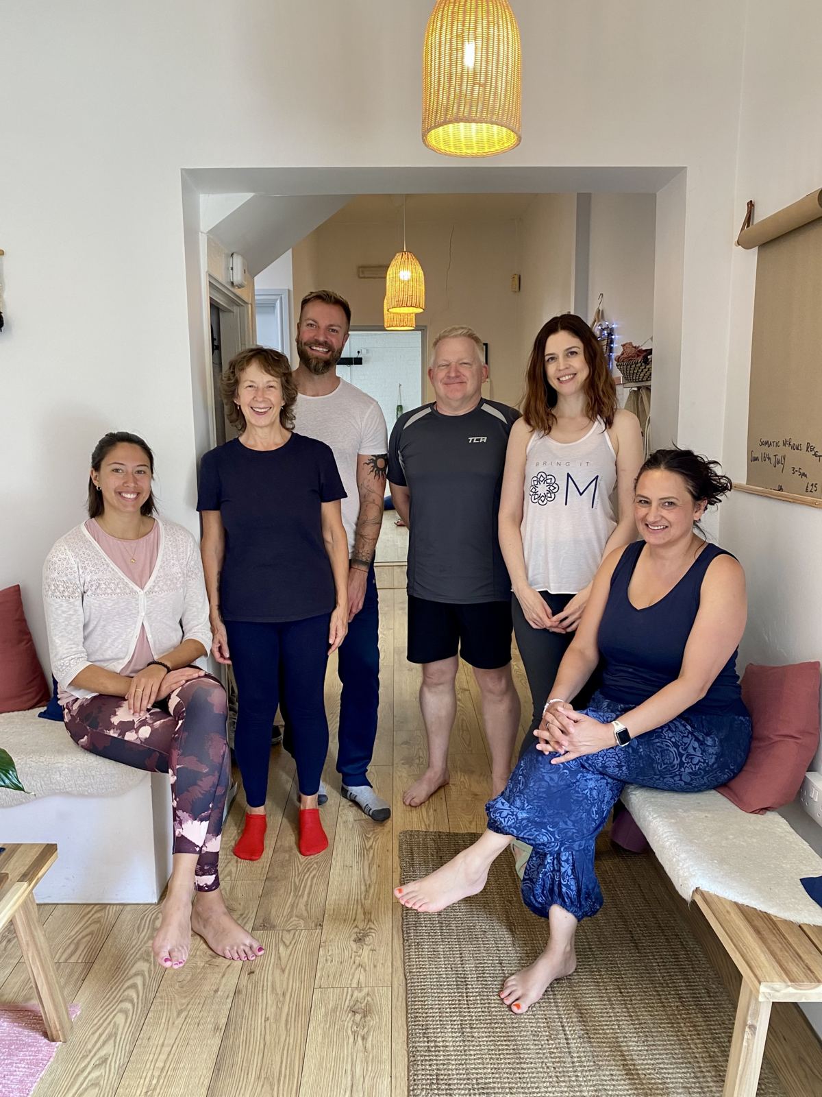 A group of teacher training graduates standing together, smiling, in the studio reception