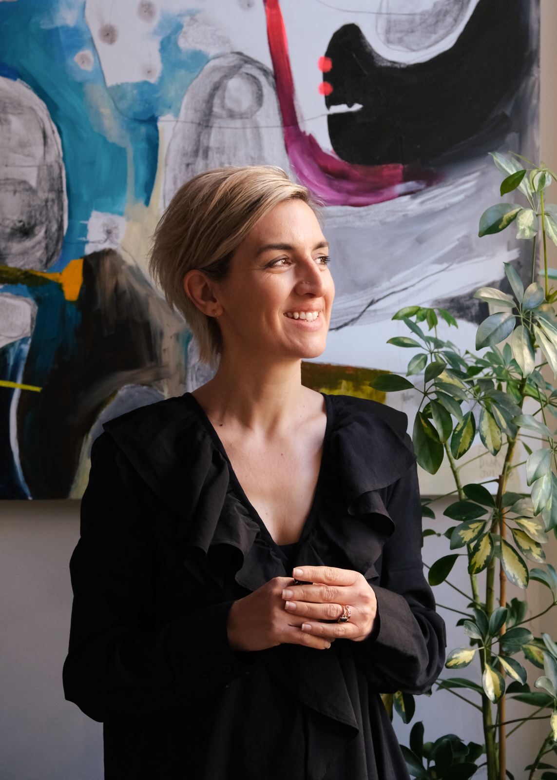 Holistic counsellor Louise Wint smiling, in front of a colourful painting