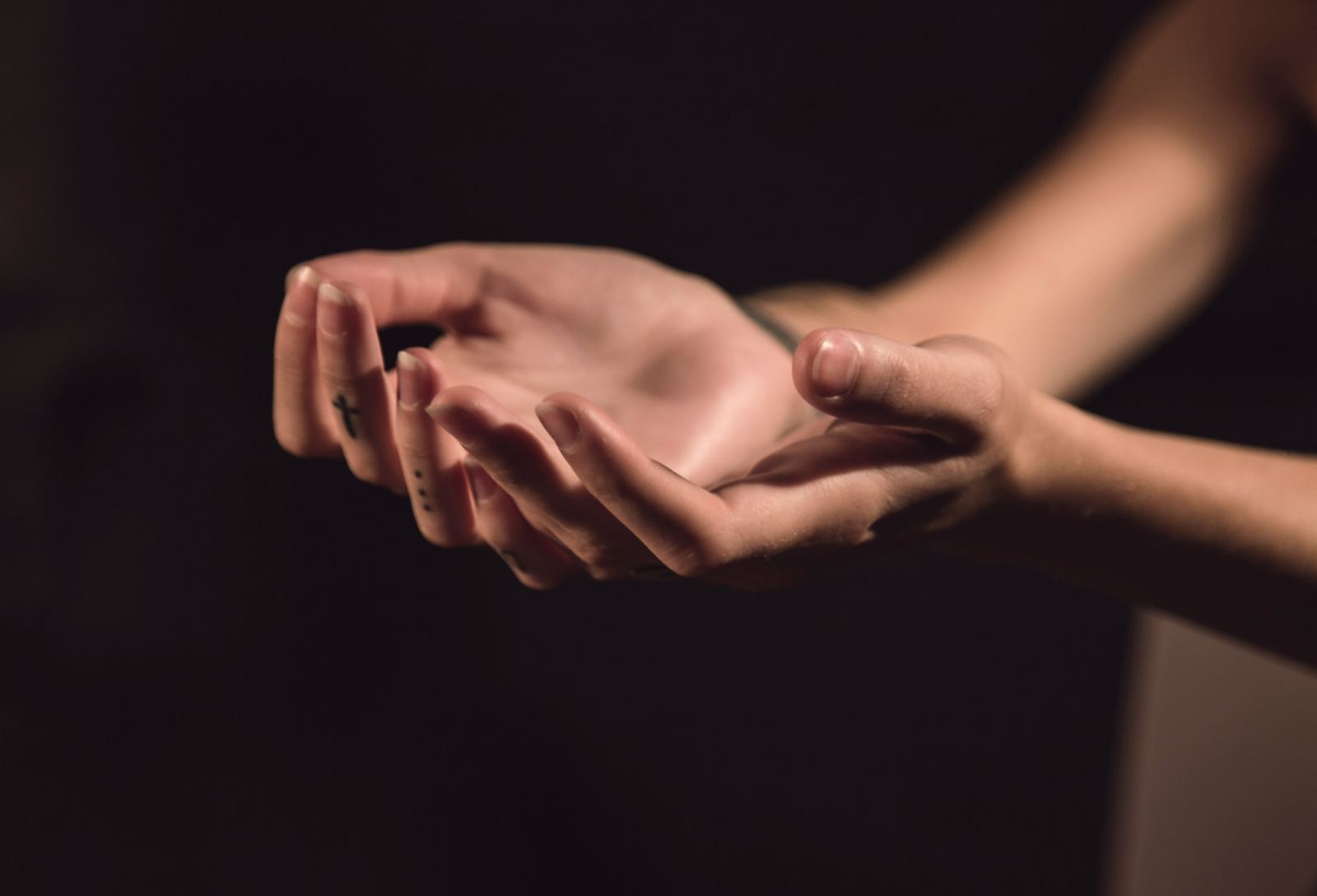 Two open, cupped hands held out gently against a dark background