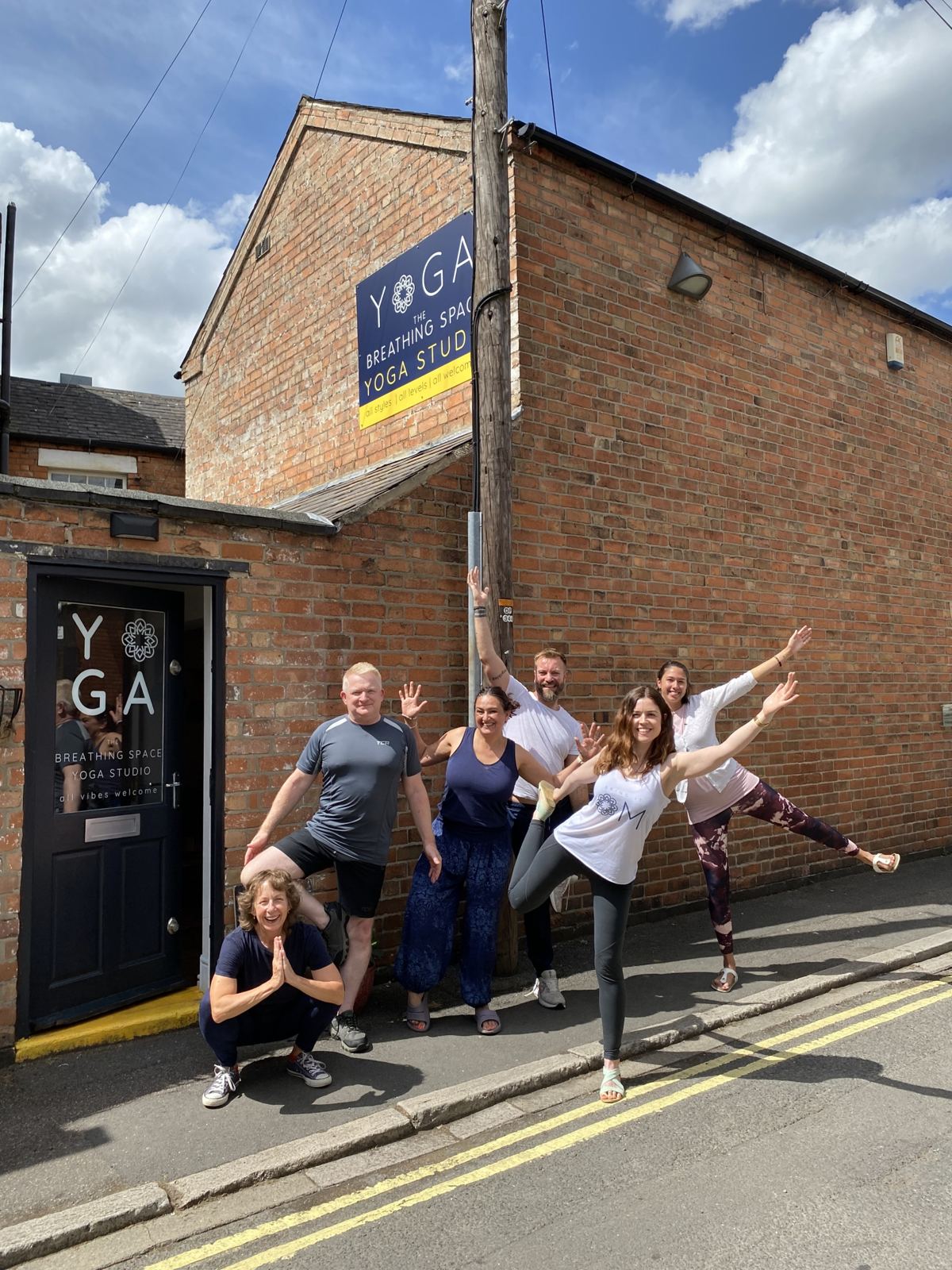 A group of students striking playful yoga poses outside The Breathing Space studio in Derby