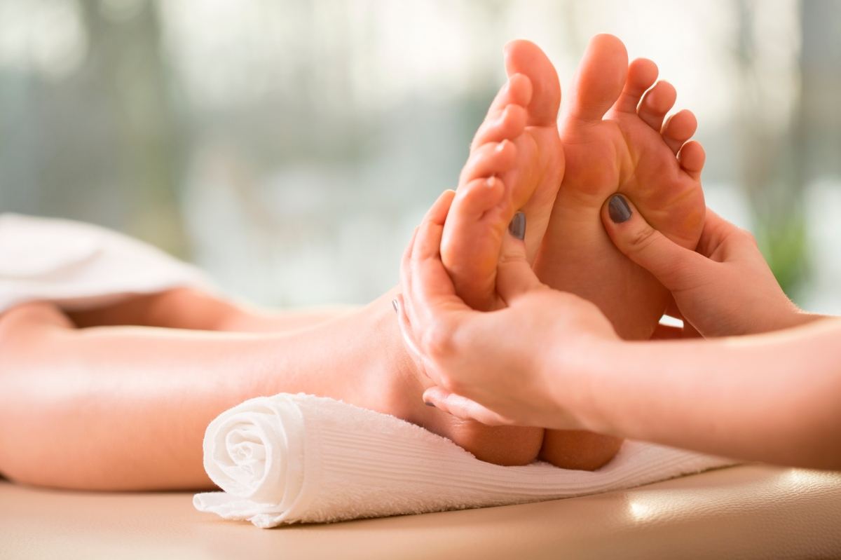 A therapist’s hands working on the sole of a client’s foot
