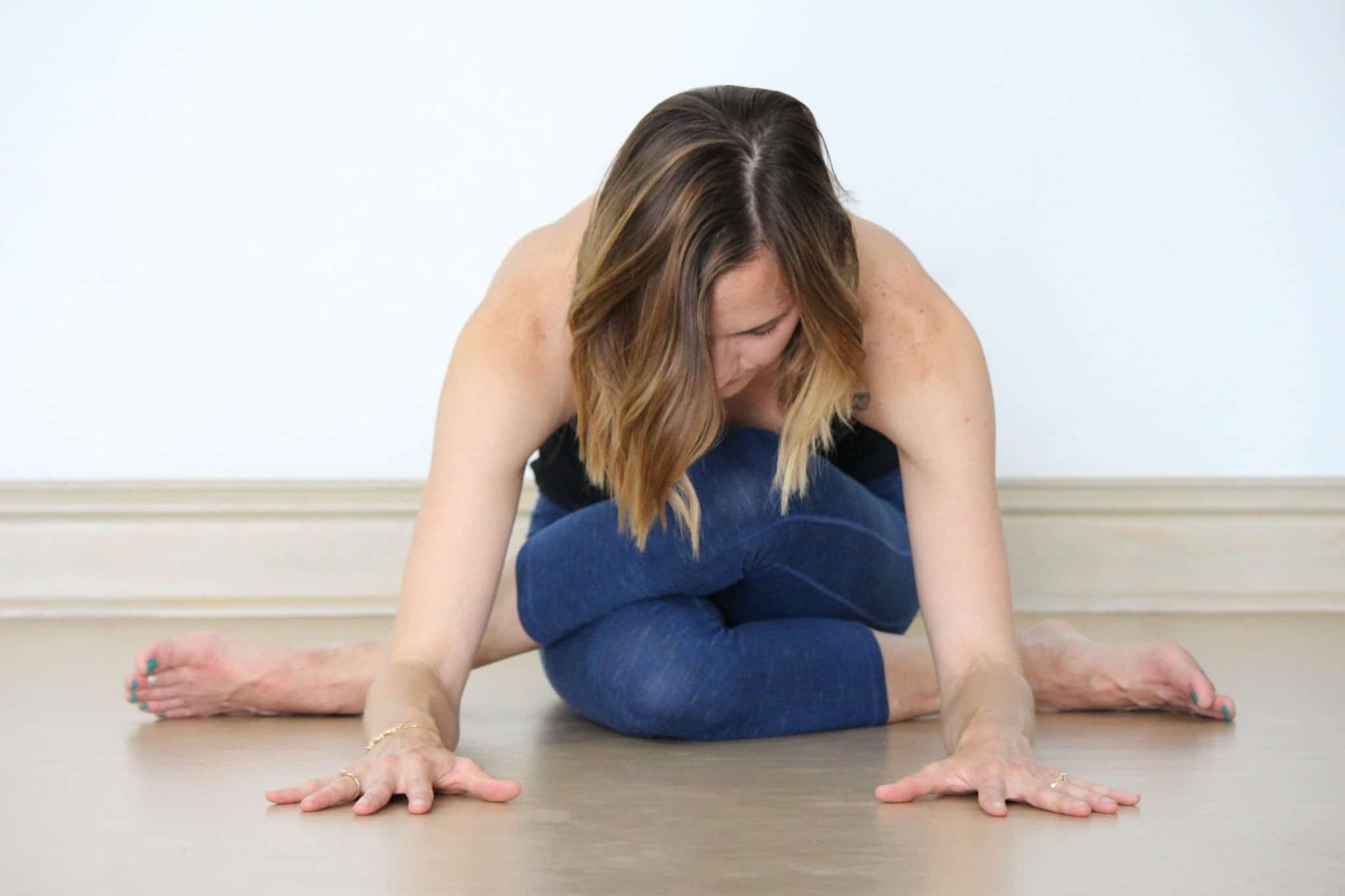 A student folding forward in cow face pose during a Yin Yoga practice